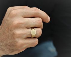 a man's hand with a ring on it, holding something in his other hand