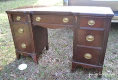 an old wooden desk with brass knobs on the top and bottom, in front of a car