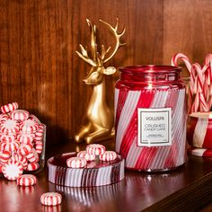 candy canes and candies sit on a shelf next to a glass jar with a candle