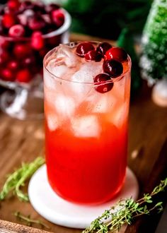 a drink sitting on top of a wooden table next to cranberries and greenery