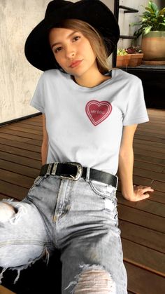 a woman sitting on top of a wooden bench wearing ripped jeans and a black hat