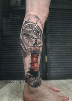 a man's leg with a lighthouse and compass tattoo on it