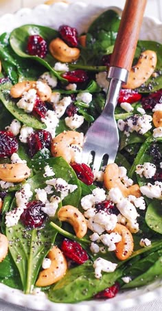 spinach salad with cranberries, nuts and feta cheese in a bowl