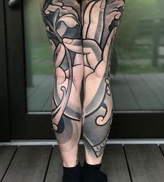 a woman with tattoos on her legs standing in front of a door