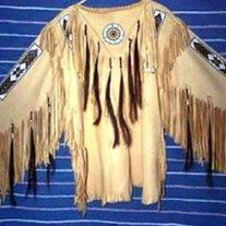 an old native american leather jacket with fringes and beads on the shoulders, hanging from a blue striped wall