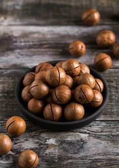 a black bowl filled with walnuts on top of a wooden table