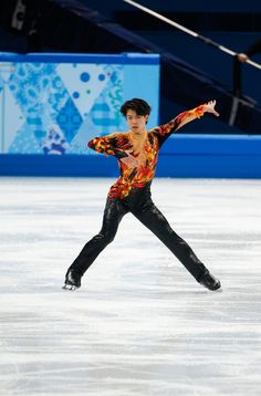 a man skating on an ice rink wearing a colorful shirt and black pants with his arms outstretched