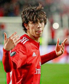 a soccer player with his hands in the air and one hand out, while standing on a field