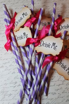 purple and white striped straws with pink bows on them are sitting in front of each other