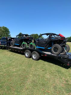 a large trailer with two atvs on it's flatbed is parked in the grass