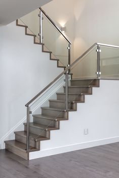 a stair case with glass balustrades and wood flooring in an empty room