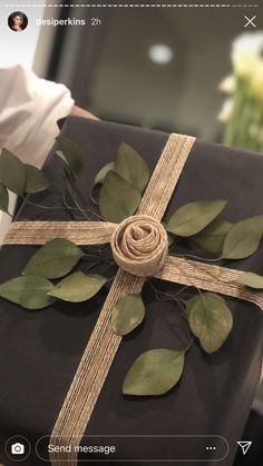 a person holding a wrapped present with leaves and twine on it's wrapper