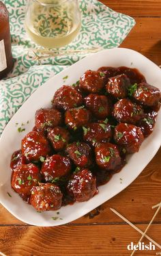 a white plate topped with meatballs next to a bottle of wine