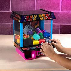 a person playing with a toy machine on a table next to a purple brick wall