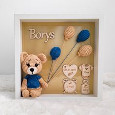 a crocheted teddy bear in a shadow box with baby's names on it