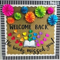 a bulletin board with colorful paper flowers and an open book on it that says, welcome back the books missed you