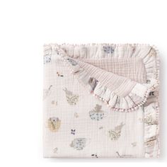 a blanket with animals on it and ruffles around the edges, sitting on top of a white surface