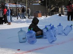 a person sitting in the snow with several water bottles