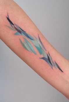 a tattoo on the arm of a woman with blue and green watercolors in it