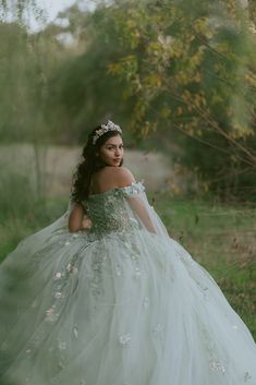 a woman in a wedding dress is walking through the grass with her hand on her hip