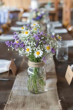 Discover simple and beautiful wildflower centerpieces for your wedding. Perfect for round and rectangle tables, these DIY flower arrangements in mason jars or vases also make stunning decorations for showers and birthdays. Simple Centerpiece Wedding Rustic, Simple Flowers For Table, Small Flower Decorations Table, Table Decoration With Flowers, Simple Wedding Reception Round Table Decor, Outside Simple Wedding Ideas, Rustic Spring Wedding Centerpieces, Simple Wedding Flowers Centerpieces Reception Ideas, Spring Flower Decorations