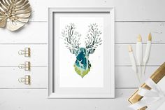 a framed art print of a deer's head with green leaves on it, next to other items