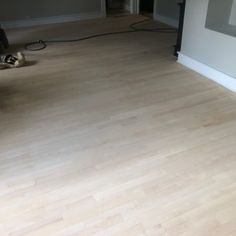 an empty room with hard wood flooring and a vacuum on the floor next to it