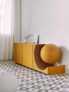 an orange ball sitting on top of a yellow cabinet