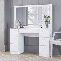 a white dressing table with a mirror and chair next to it on top of a rug