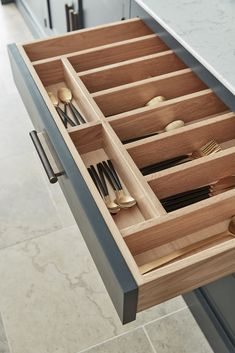 an open drawer with utensils and spoons in it on a countertop