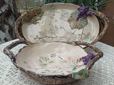 two bowls sitting on top of a table next to a potted plant with purple flowers