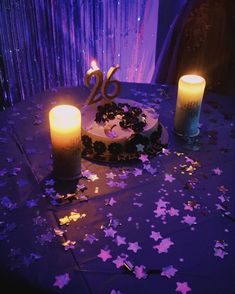 a birthday cake sitting on top of a table next to two candles and some confetti