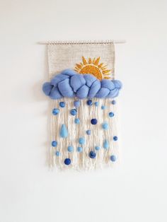 a wall hanging with blue beads and a yellow sun on the cloud in the sky