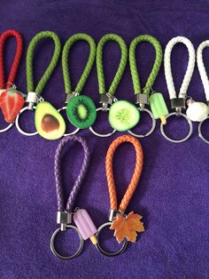 several key chains with fruits and vegetables attached to them on a purple cloth covered surface