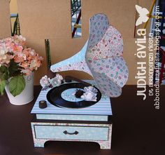 a record player sitting on top of a table next to a vase with flowers in it