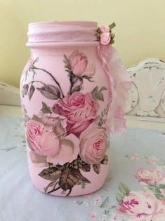 a pink jar with flowers painted on it sitting on a tablecloth covered table cloth