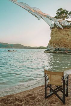 a chair sitting on top of a sandy beach next to the ocean