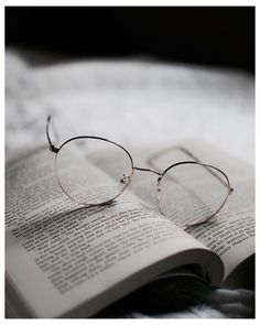 an open book with glasses on top of it