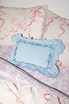 a bed with pink and blue sheets, pillows and a pillow case