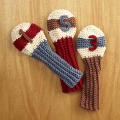 three crocheted mittens sitting on top of a wooden table next to each other