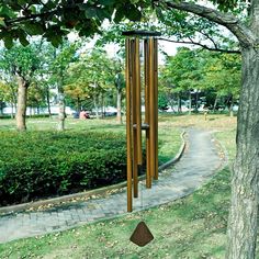 a wind chime hanging from the side of a tree next to a park path