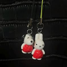 two key chains are attached to the back of a black leather bag with a white rabbit holding a red heart