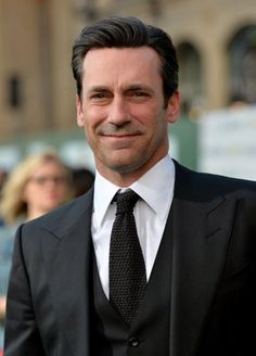 a man in a suit and tie smiling at the camera