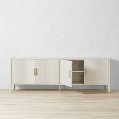 a white cabinet sitting on top of a hard wood floor next to a wall with an open door