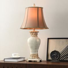 a lamp sitting on top of a wooden table next to a clock and framed photograph