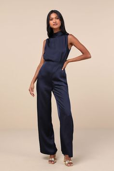 You'll feel like total royalty in the Lulus Classic Elegance Navy Blue Satin Sleeveless Mock Neck Jumpsuit! Luxe woven satin shapes this chic jumpsuit that has a mock neckline and a sleeveless bodice with gathered fabric detailing. Fitted waist tops wide legs that end at ankle-length hems. Keyhole opening and double button closure at back. Hidden back zipper/clasp. Fit: This garment fits true to size. Length: Floor length. Size medium measures 61.25" from shoulder to hem. Inseam: 32.00 Front Ris Navy Formal Jumpsuit, Navy Blue Monochromatic Outfit, Blue Jumpsuit Outfit Wedding, Navy Blue Outfits For Women Classy, Navy Jumpsuit Outfit, Winter Cocktail Attire, Formal Jumpsuits For Women Classy, Blue Jumpsuit Outfit, Blue Jumpsuits Outfit