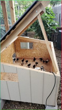 a chicken coop built into the side of a house with chickens in it's nesting box