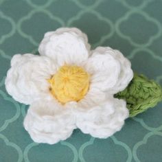 a crocheted white flower sitting on top of a green tablecloth covered floor