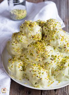 a white plate topped with dessert covered in frosting and sprinkles on top of a wooden table