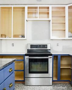 an empty kitchen with blue cabinets and stainless steel stove top oven in the middle,